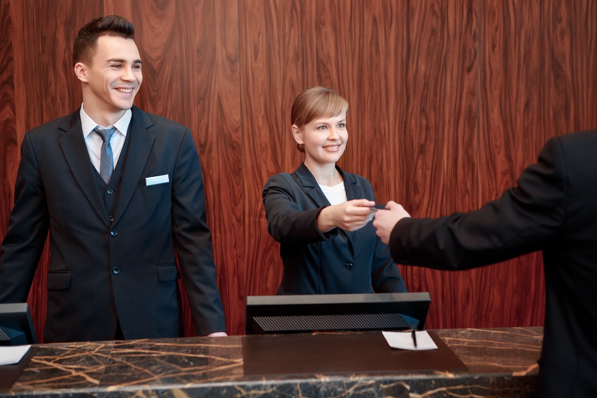 Here is your key.  Receptionists welcome guest with a smile while giving a key